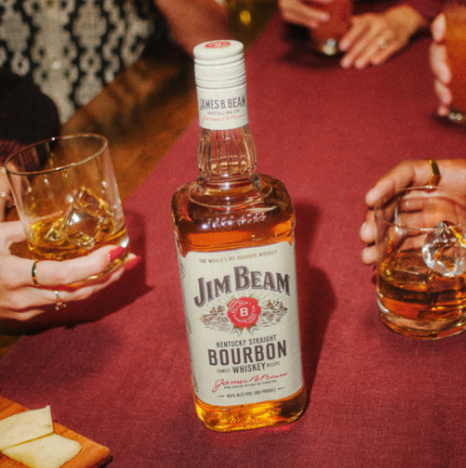 A Jim Bean Bourbon whiskey bottle, alongside two hands, each holding a glass of Jim Bean whiskey.